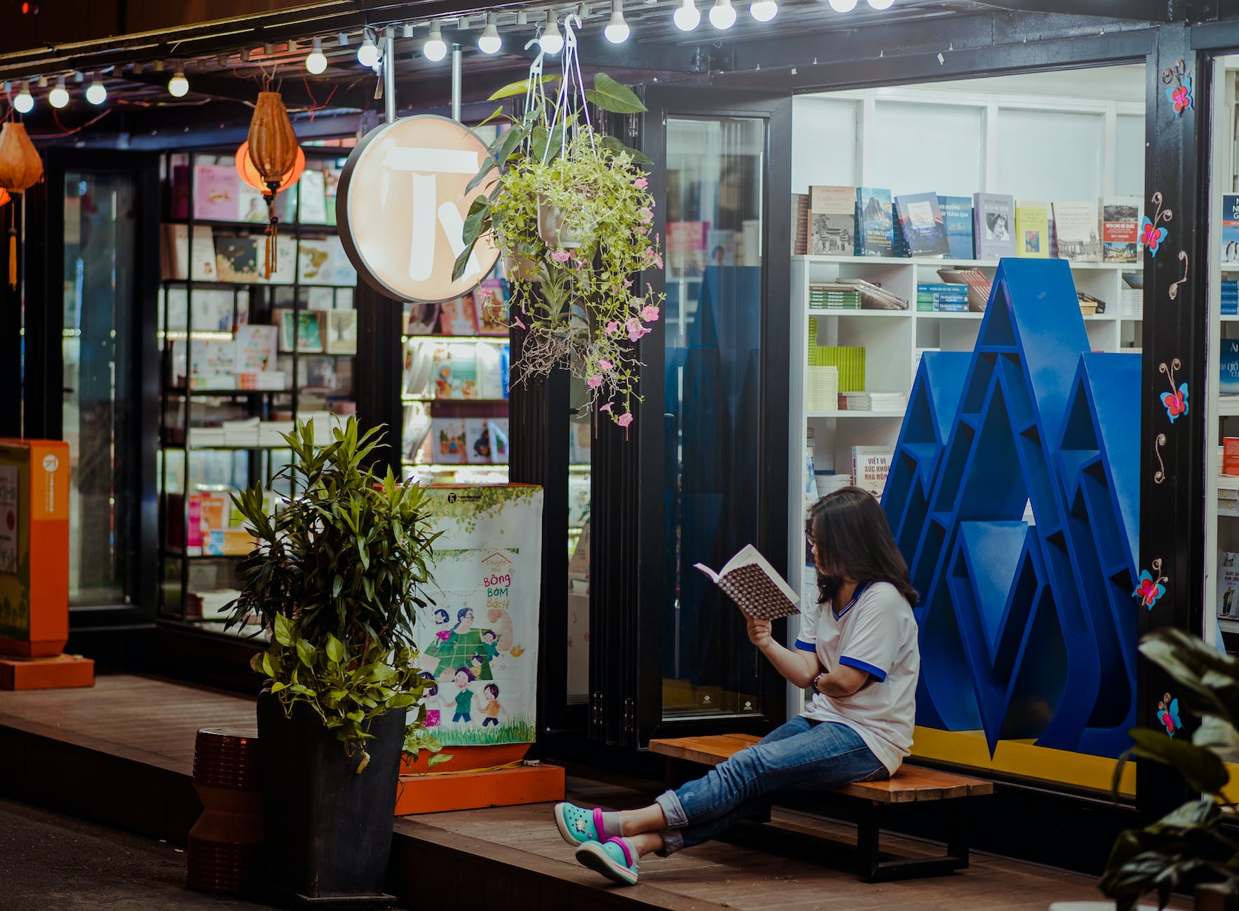 woman sitting down on bench and reading infront of store